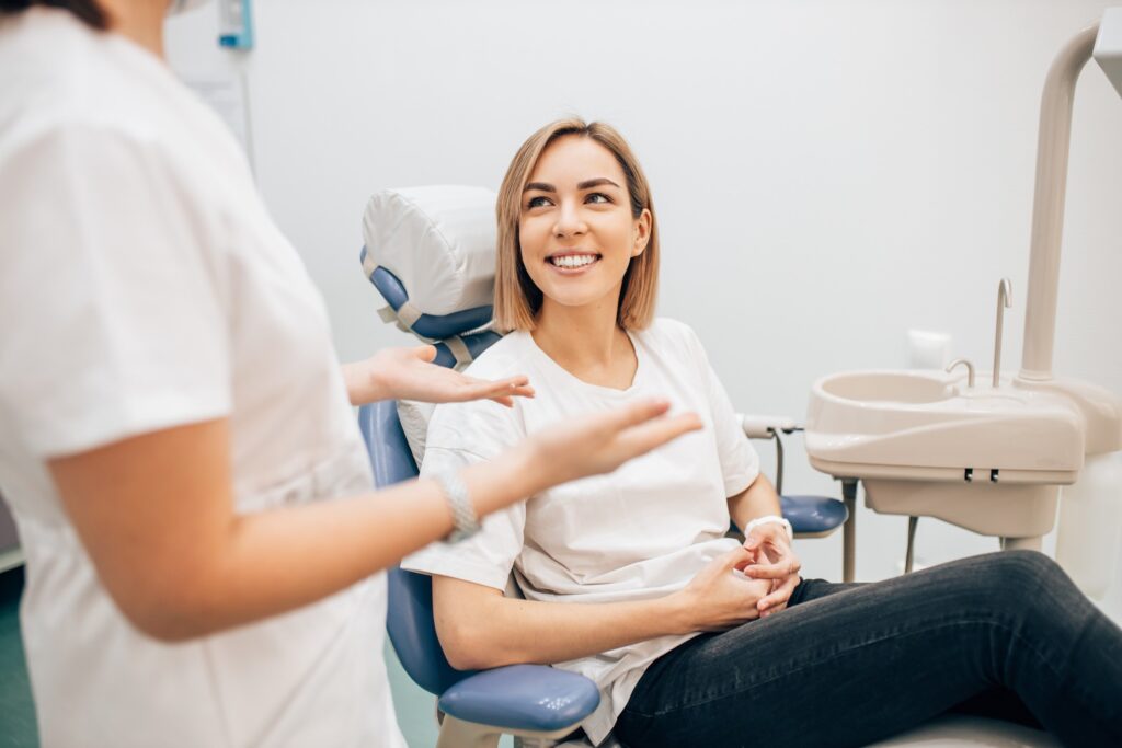 Patient in treatment chair smiling at dental assistant